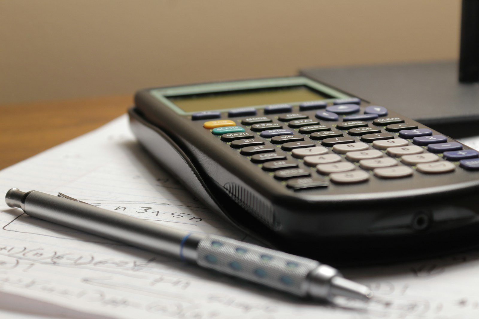 Emitir Nota Fiscal MEI: 7 Passos (e 3 Erros do Portal) Calculadora e caneta sobre papel com cálculos do MEI