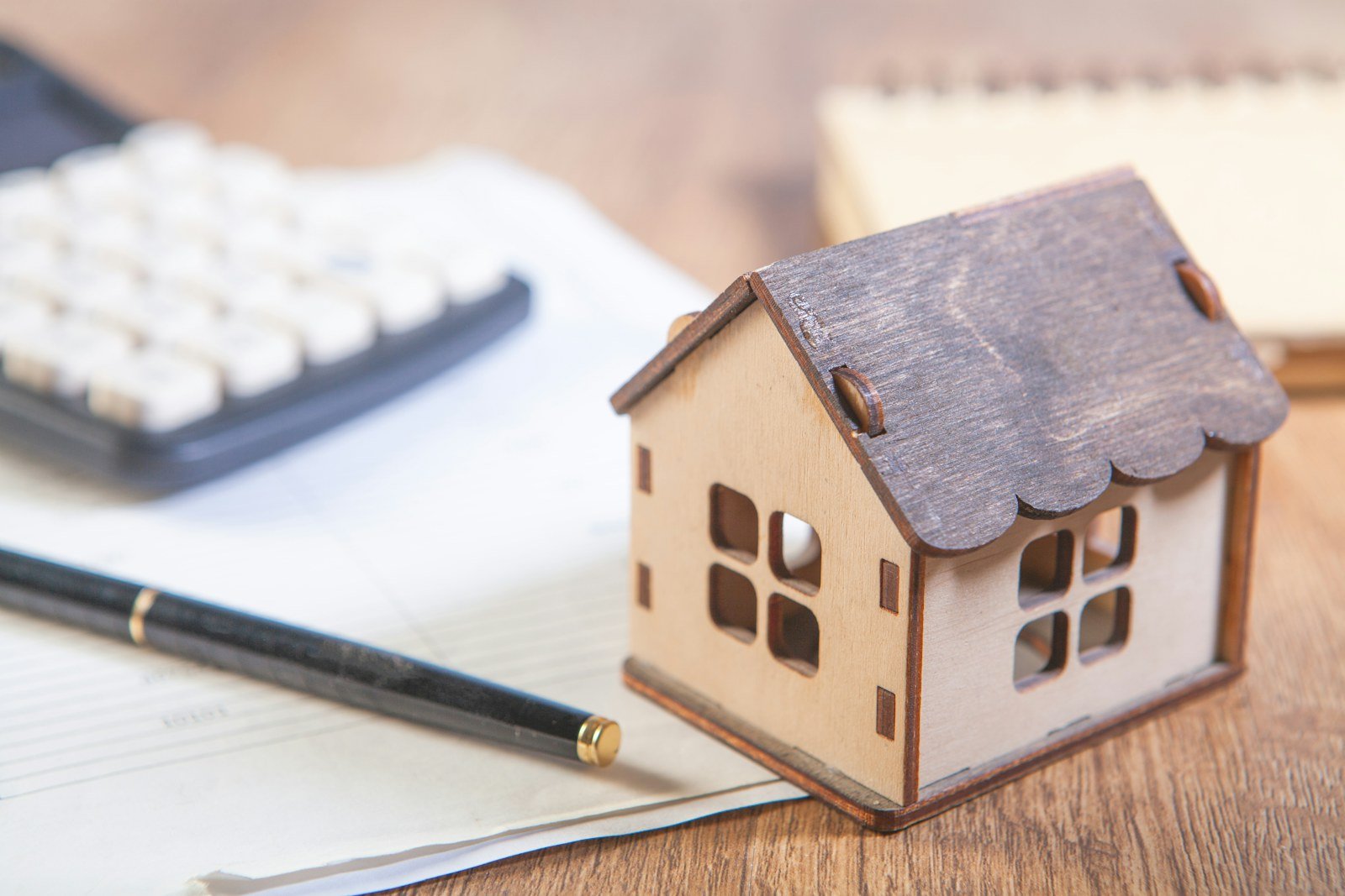 Modelos de Planilha Financeira: 7 Testados (4 Servem) Casa em miniatura ao lado de calculadora, decidindo entre modelos de planilha financeira