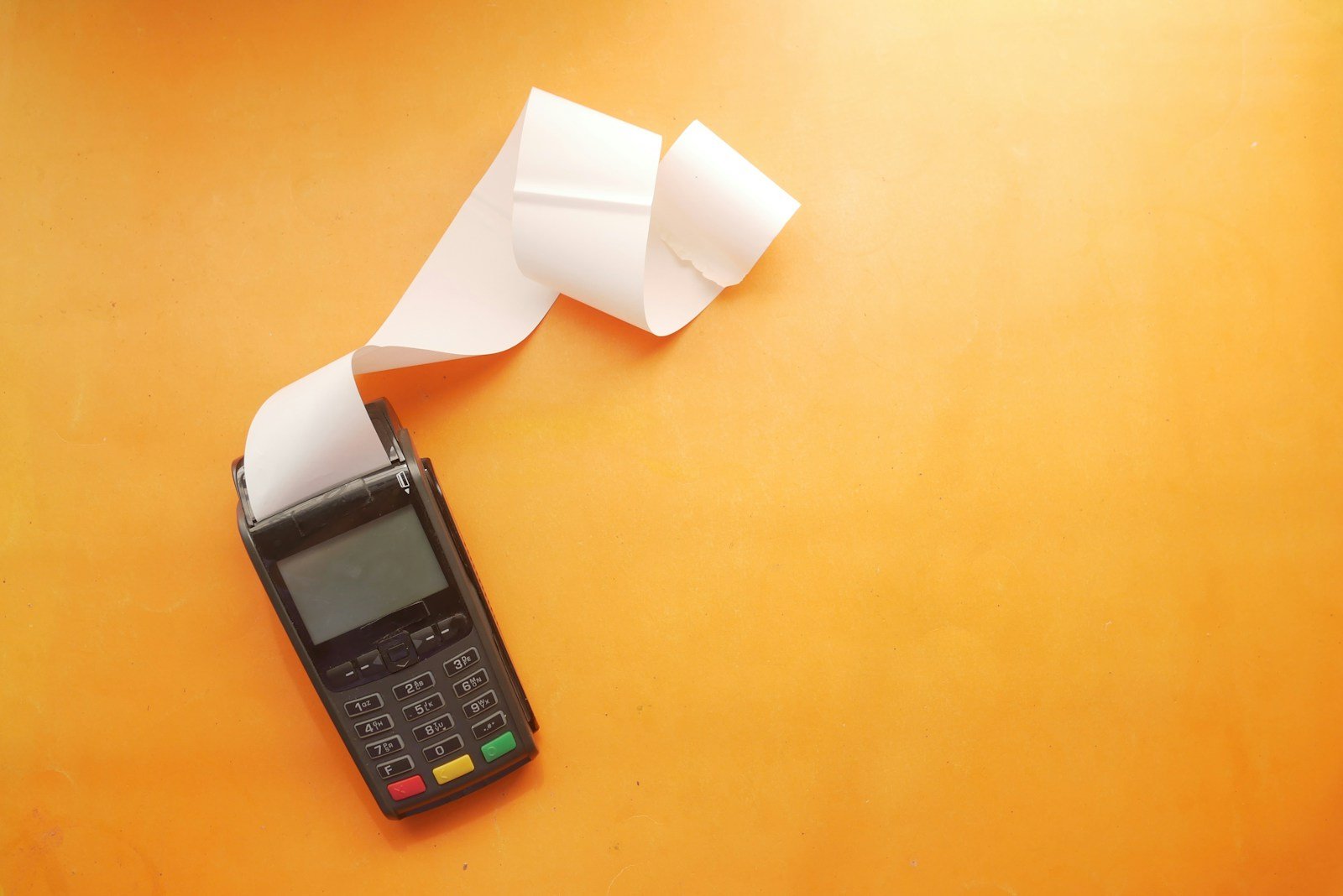 Como Pagar DAS Atrasado MEI: Multa, Juros e o Custo Real Celular sobre mesa com boleto em rolo, simbolizando parcelar DAS atrasado MEI pelo PGMEI