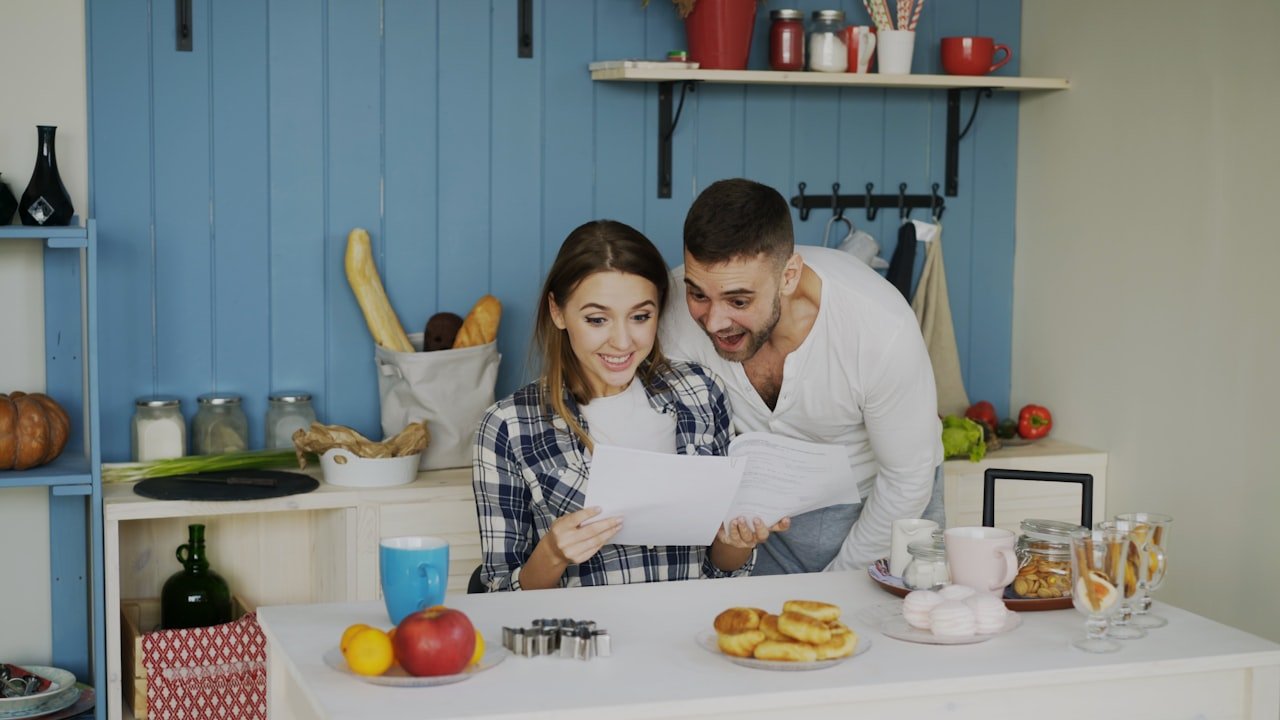 Casal revisando a planilha financeira familiar na cozinha