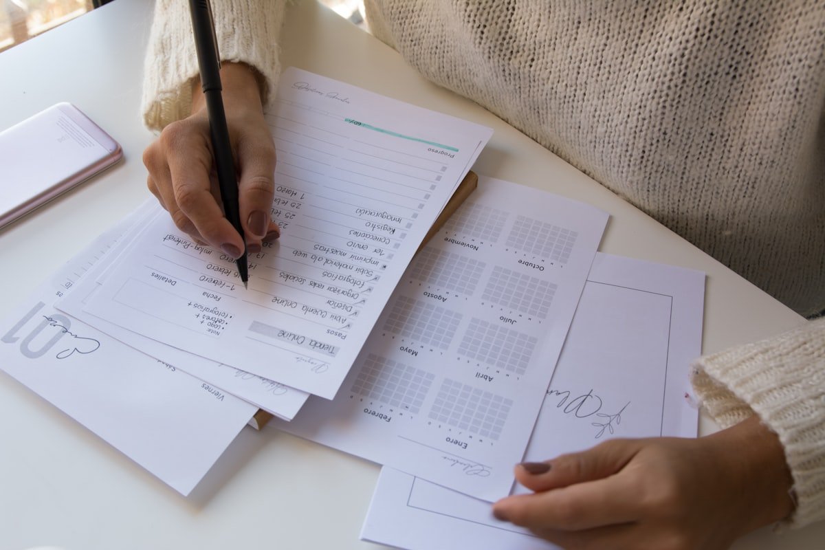 Planilha Financeira para Imprimir: Quando o Papel Vence Mão anotando gastos numa planilha financeira impressa