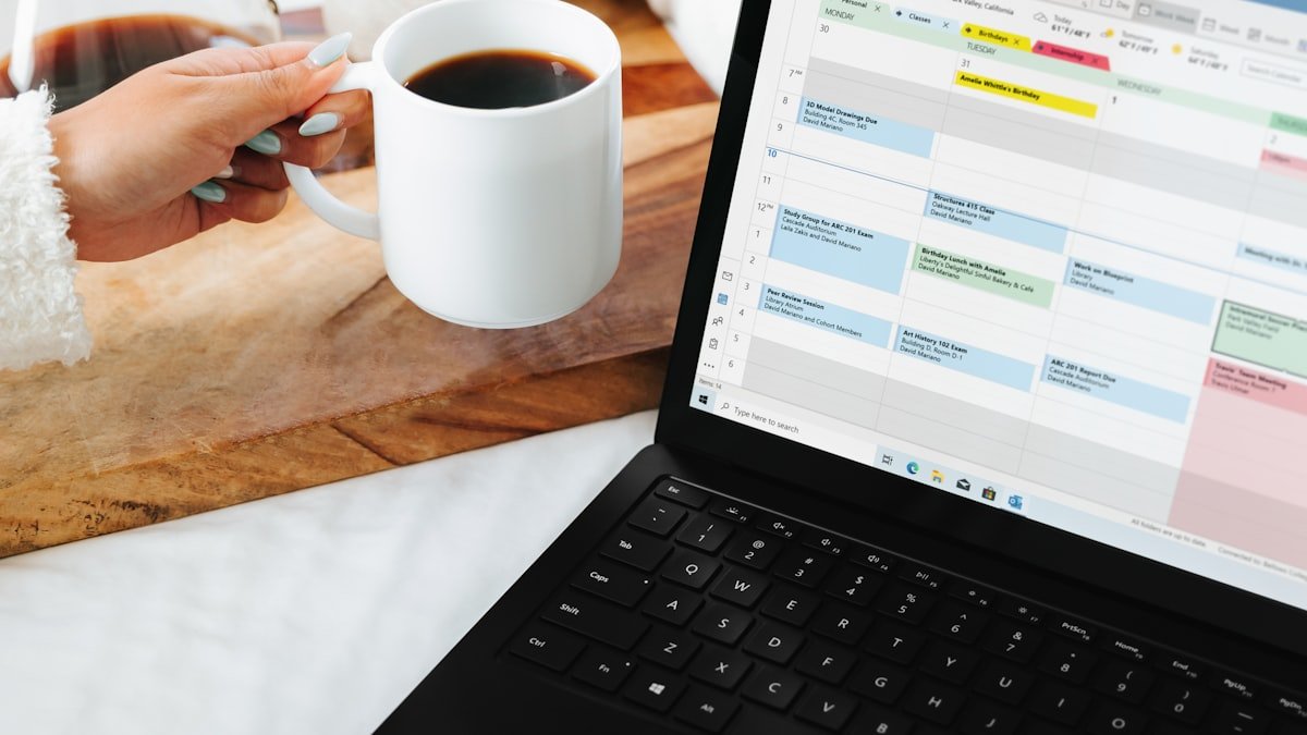 Planilha de gastos pessoais aberta em um notebook ao lado de uma xicara de cafe