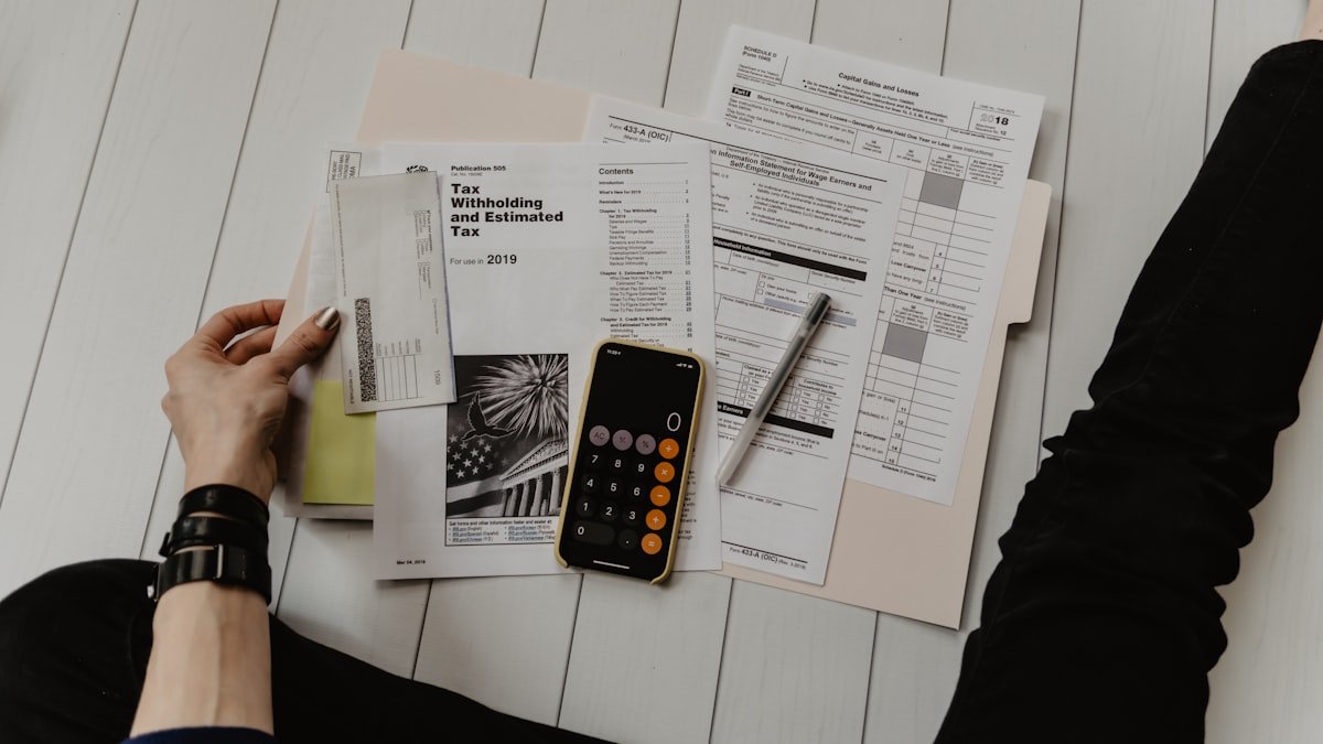Custos fixos e variáveis anotados com calculadora, contas e caderno sobre a mesa