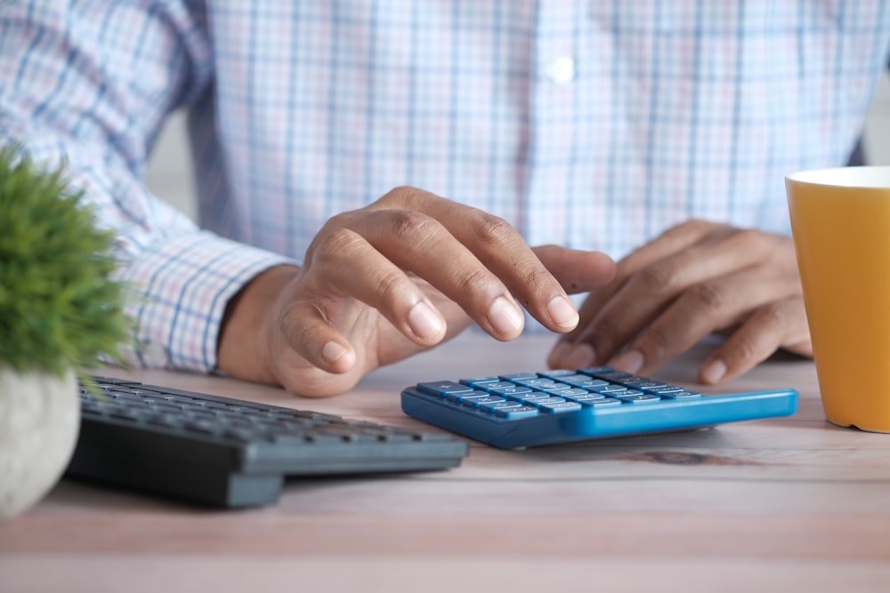 Como Precificar um Produto Sem Vender no Prejuízo Calculadora e anotações usadas para calcular o custo na precificação de um produto