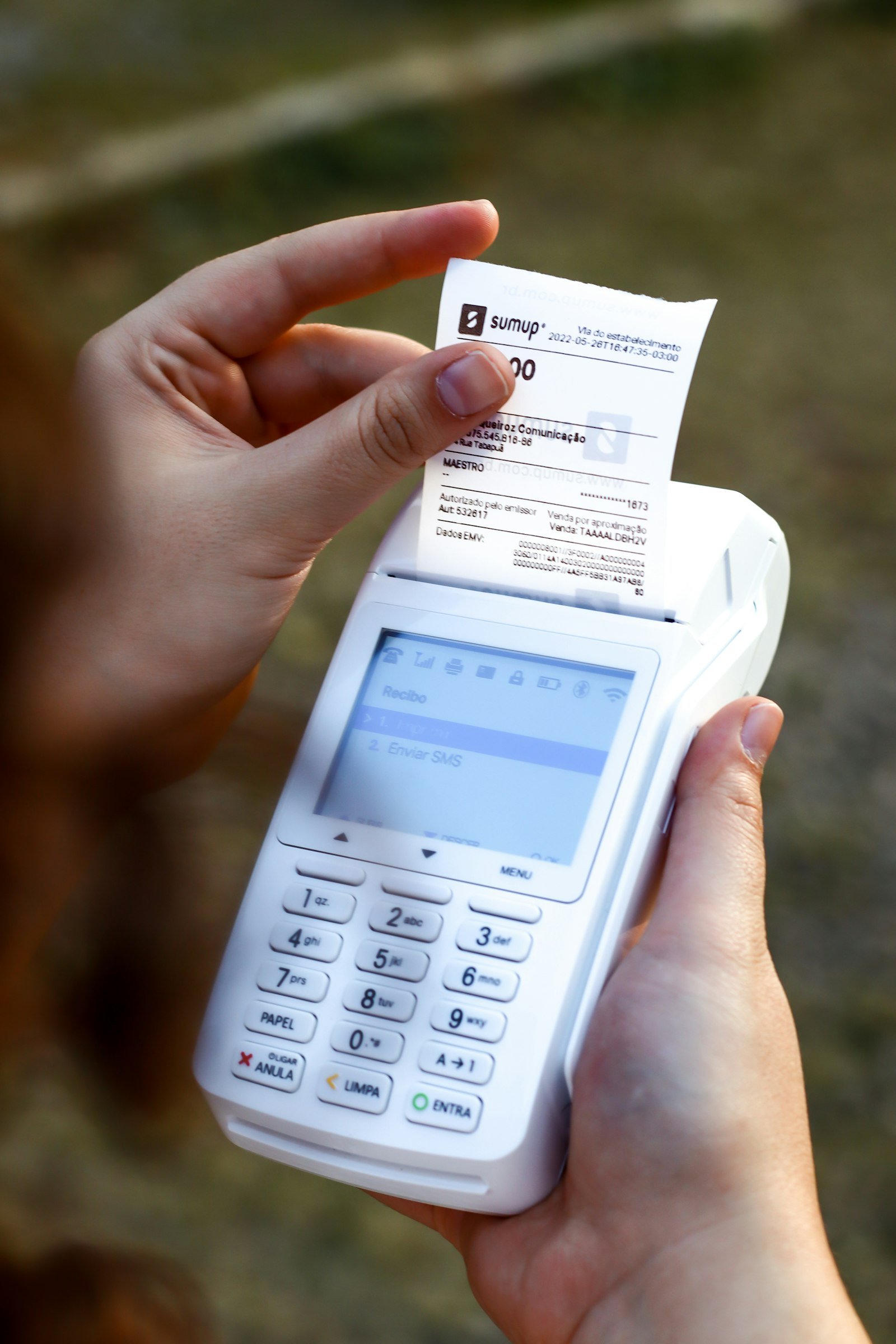 Comprovante na mão ao lado do celular para comparar o saldo disponível com os lançamentos