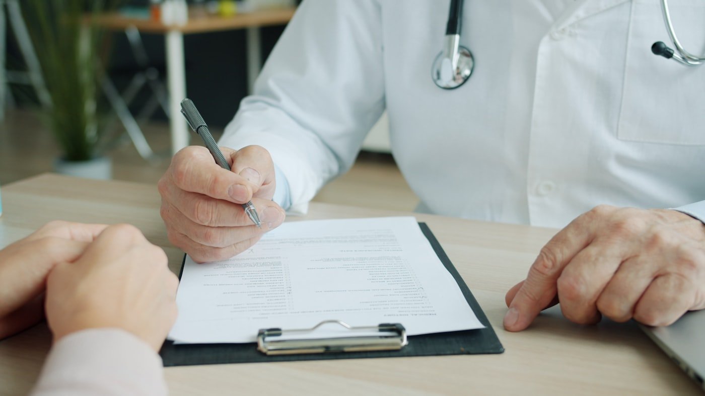 Quando o Vale Alimentação é Obrigatório: 5 Casos (e 1 Mito) Médico escrevendo atestado, o documento que mais provoca corte de vale alimentação