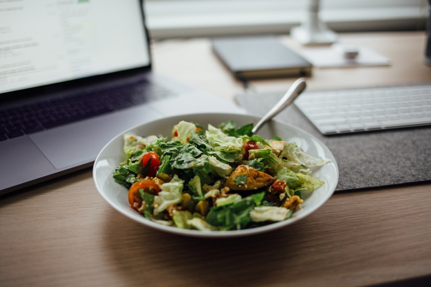 Quando o Vale Alimentação é Obrigatório: 5 Casos (e 1 Mito) Refeição sobre a mesa ao lado do notebook, o almoço que o vale alimentação deveria cobrir