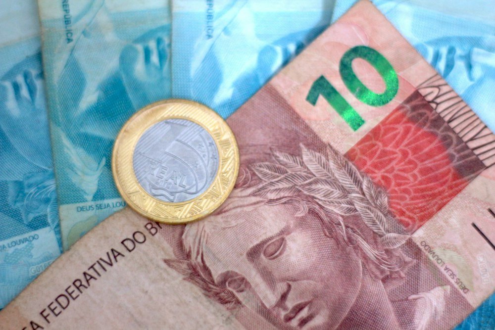 Nota de real e moeda ilustrando o cálculo do valor do abono salarial por mês trabalhado