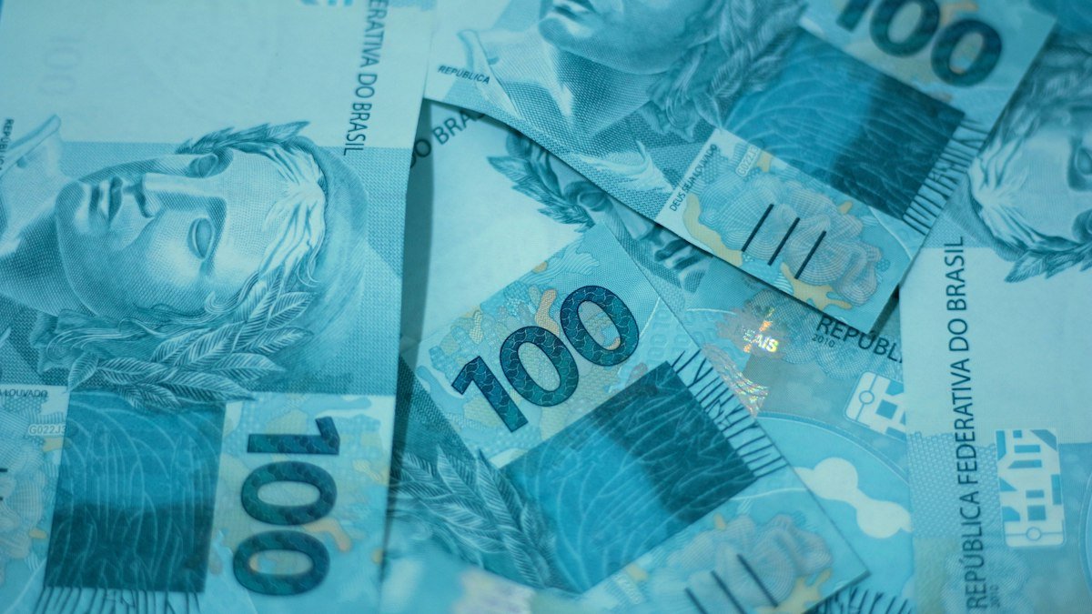 Notas de 100 reais representando o abono salarial do PIS pago ao trabalhador