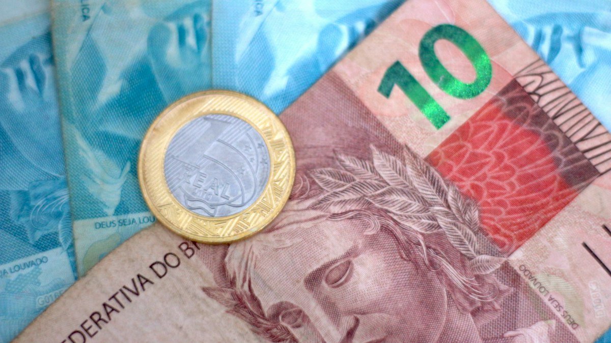 Nota de real com moeda em cima, símbolo do que é inflação no bolso