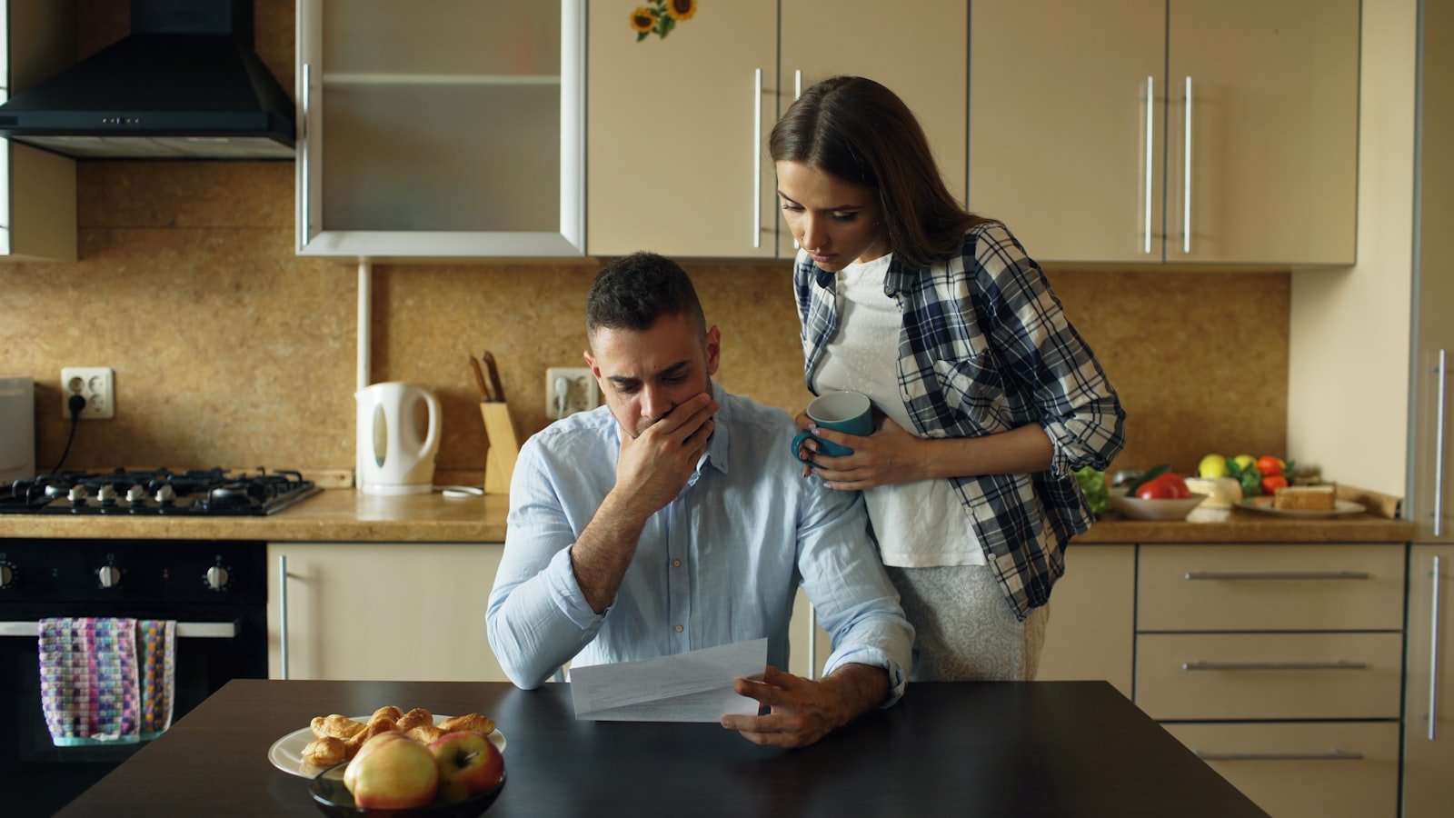 Casal conferindo contas na mesa da cozinha depois de morar junto