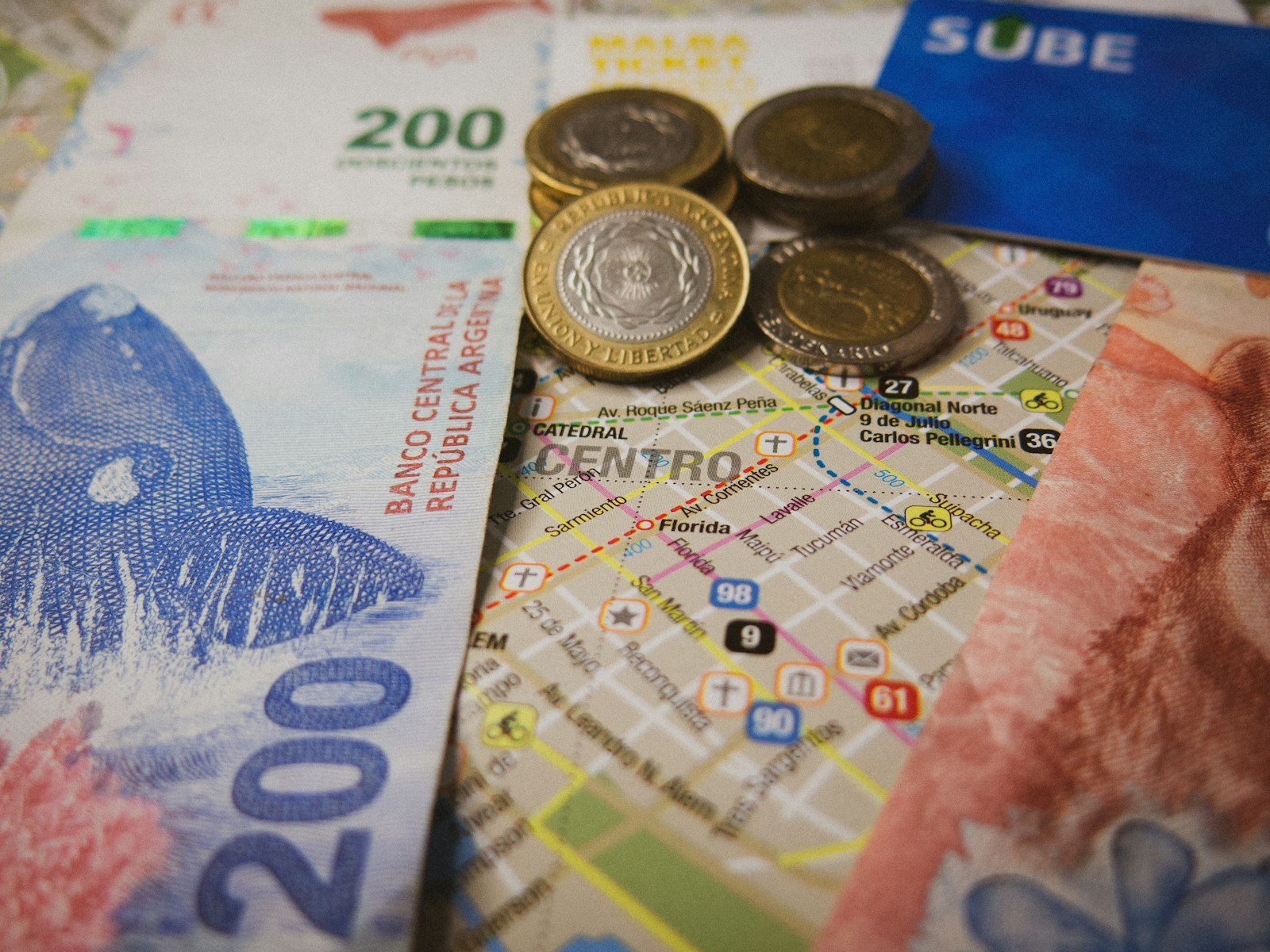 O Que É IOF: 3,5% no Cartão e a Queda Que Foi Cancelada Mapa com moedas e notas estrangeiras sobre a mesa, ilustrando o IOF do câmbio na viagem