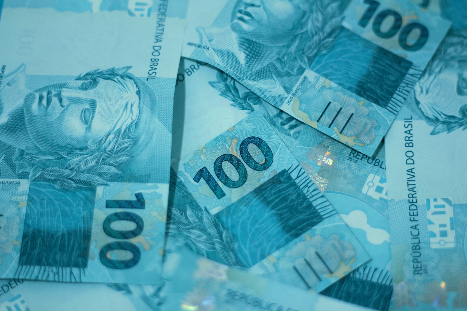 Notas de cem reais empilhadas, ilustrando quando cai o décimo terceiro