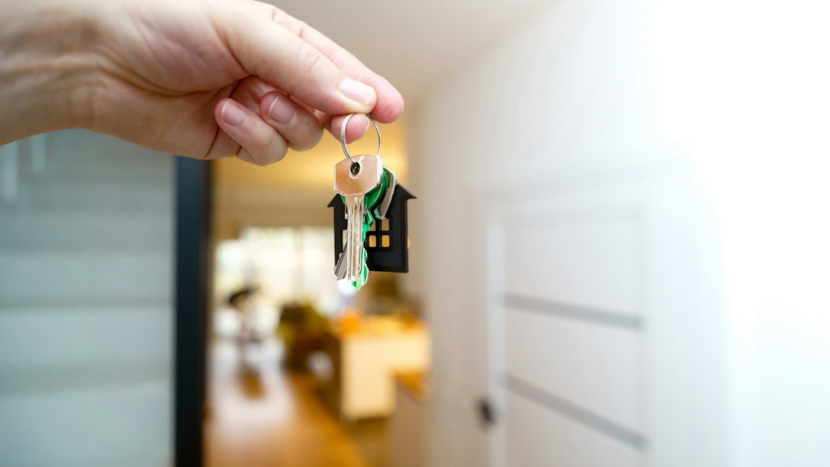 Mão segurando a chave de casa na porta do imóvel alugado, garantia de caução de aluguel
