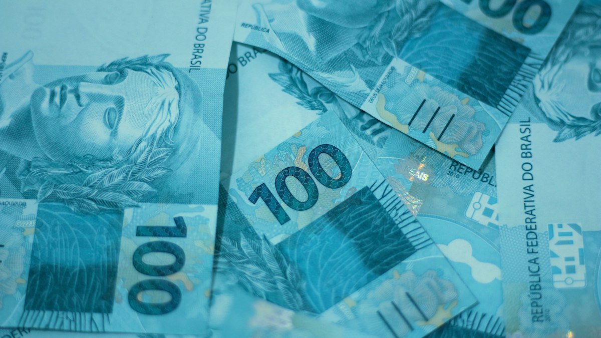 O que é taxa Selic: notas de 100 reais empilhadas representando os juros básicos da economia