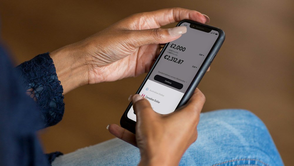 Mão segurando celular com aplicativo de banco, sobre como pedir o pagamento ao FGC