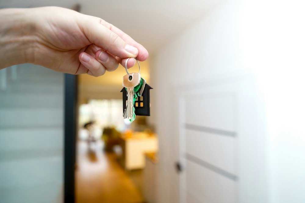 O Que É Taxa Selic: 13,75% e o Que Isso Muda no Seu Bolso Mão segurando as chaves de casa, sobre o efeito da taxa Selic no financiamento imobiliário