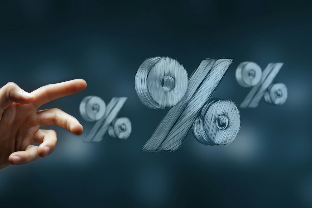 O Que É Taxa Selic: 13,75% e o Que Isso Muda no Seu Bolso Mão alcançando símbolos de porcentagem, sobre como a taxa Selic define o piso dos juros
